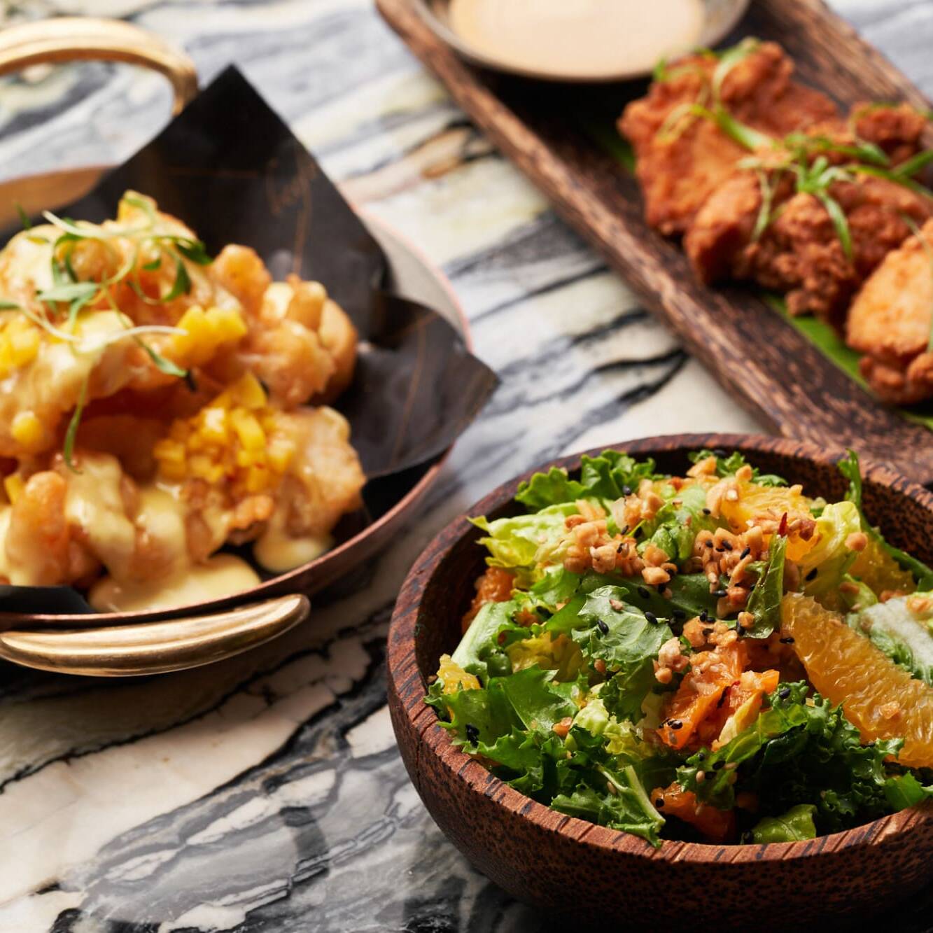 three dishes on a table: salad and chicken with sauce